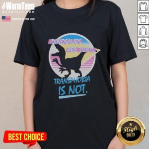 Funny dinosaurs graphic on a women's tee with text: 'Dinosaurs Are Cool, Transphobia Is Not' promoting inclusivity.