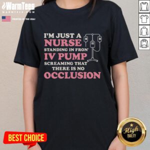 Nurse wearing a 'Good I'm Just A Nurse' tee stands confidently in front of an IV pump, showcasing dedication to healthcare.