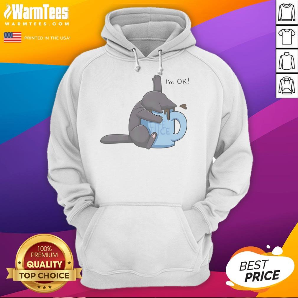 Cute cat peeking out of a coffee cup while wearing an I'm OK hoodie, showcasing adorable pet fashion.