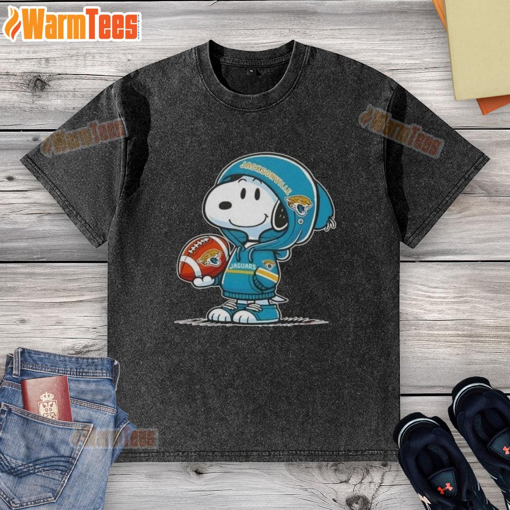 Cute Peanuts Snoopy wearing a Jacksonville Jaguars hoodie, smiling at fans while showcasing a washed t-shirt.