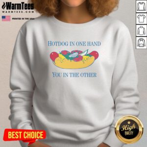 Person holding a nice hotdog in one hand and wearing a stylish sweatshirt in the other, showcasing casual dining.