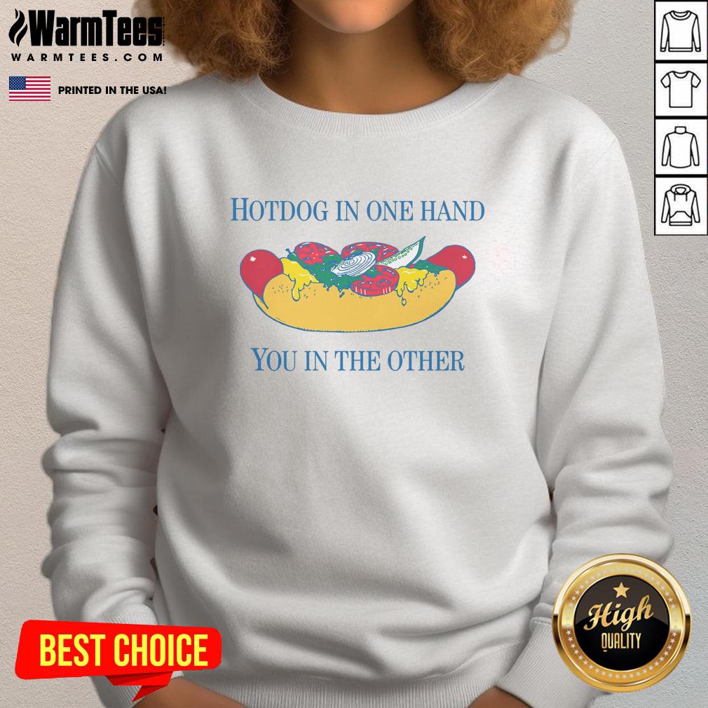 Person holding a nice hotdog in one hand and wearing a stylish sweatshirt in the other, showcasing casual dining.