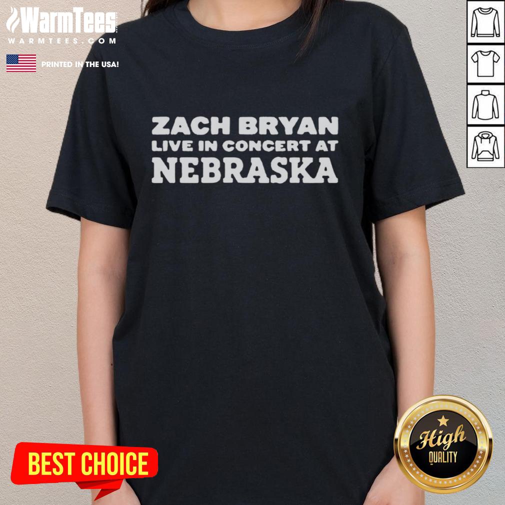 Zach Bryan performing live at a Nebraska concert, wearing a stylish ladies tee, captivating the audience with his music.
