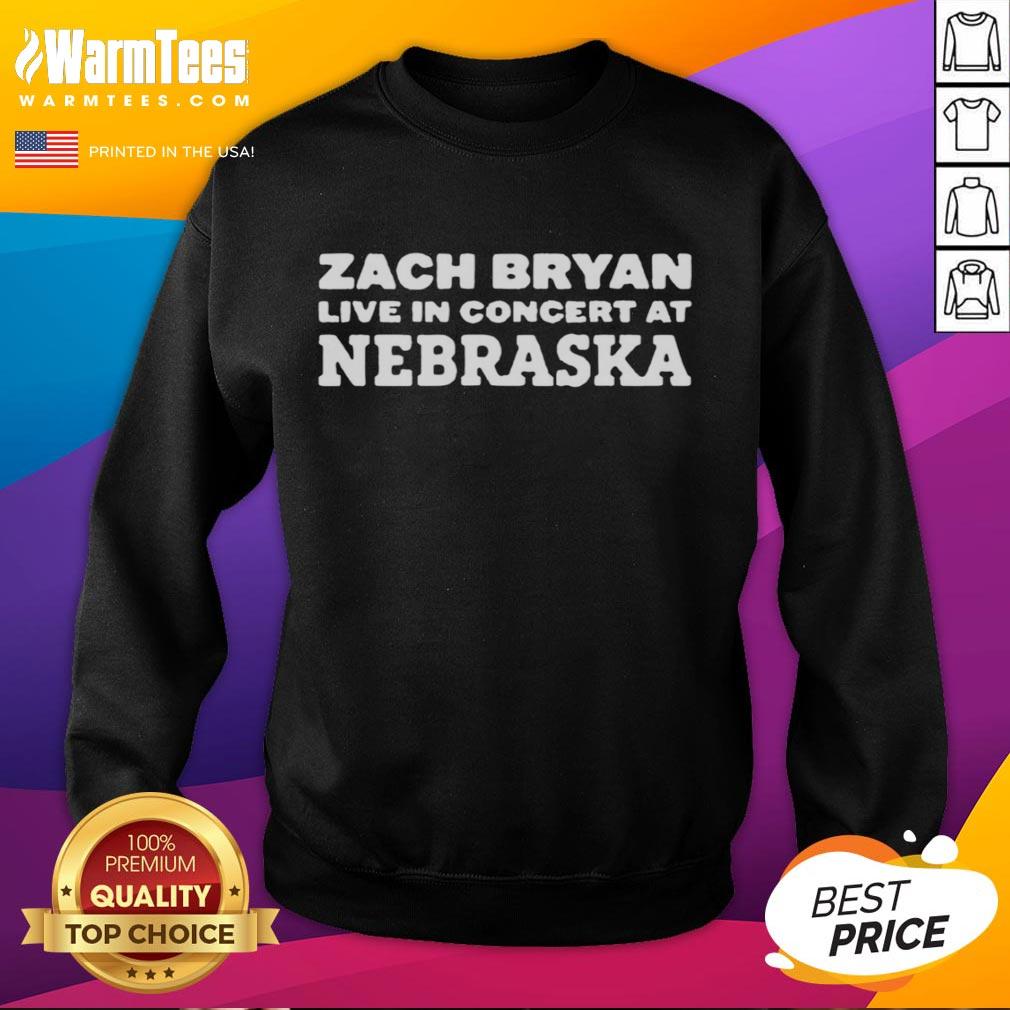 Zach Bryan performing live in Nebraska, wearing a stylish sweatshirt at an energetic concert atmosphere.